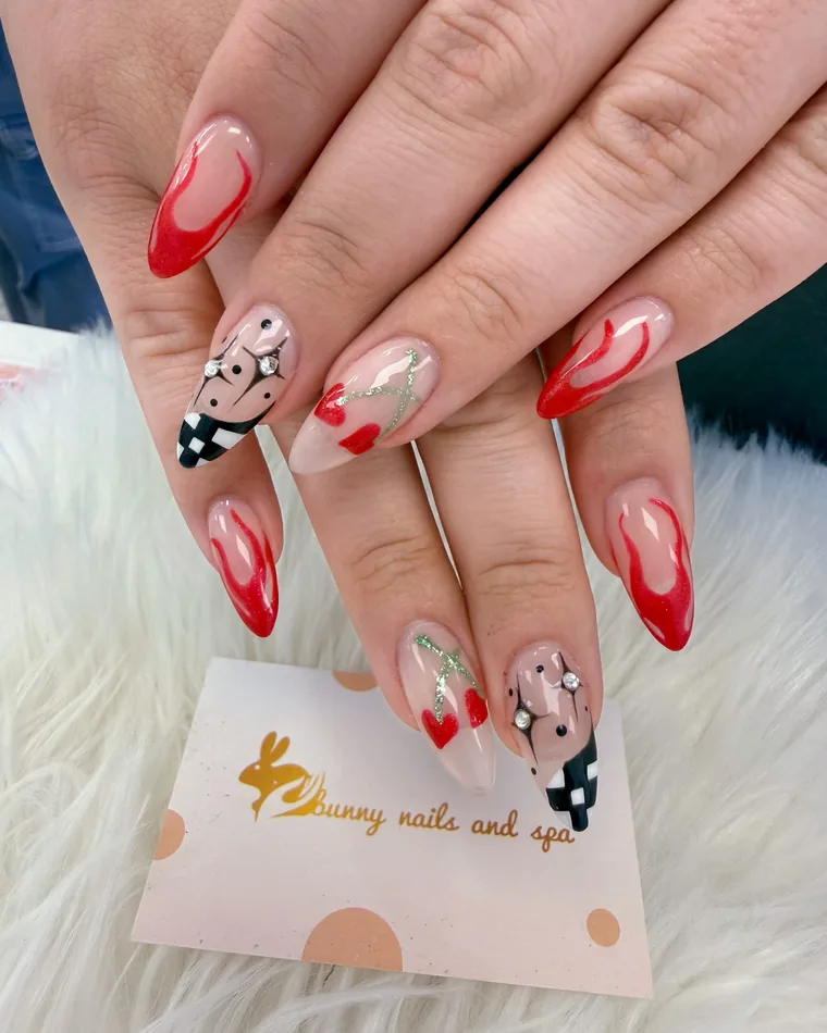 Almond nails with red flame tips, hand-painted hearts and a black-and-white checkerboard accent