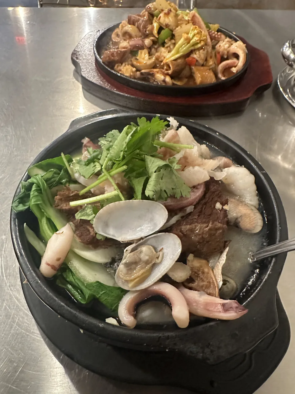A seafood hot bowl with clams, squid and greens