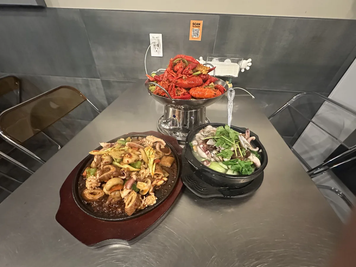 A table set with crayfish, a sizzling plate and a hot bowl