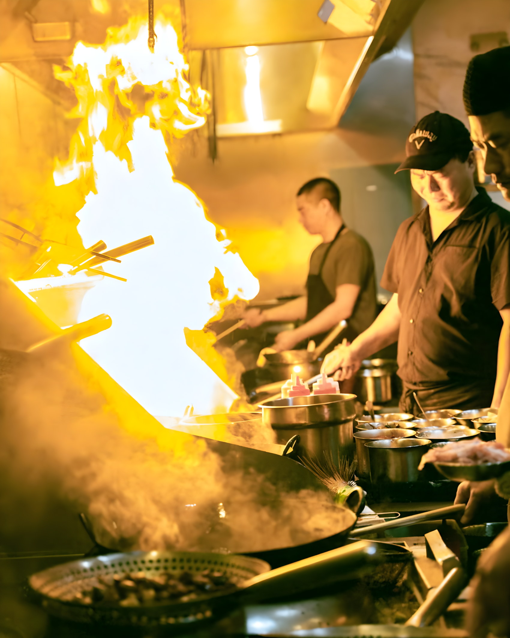 Cooks working over open wok flames in the kitchen