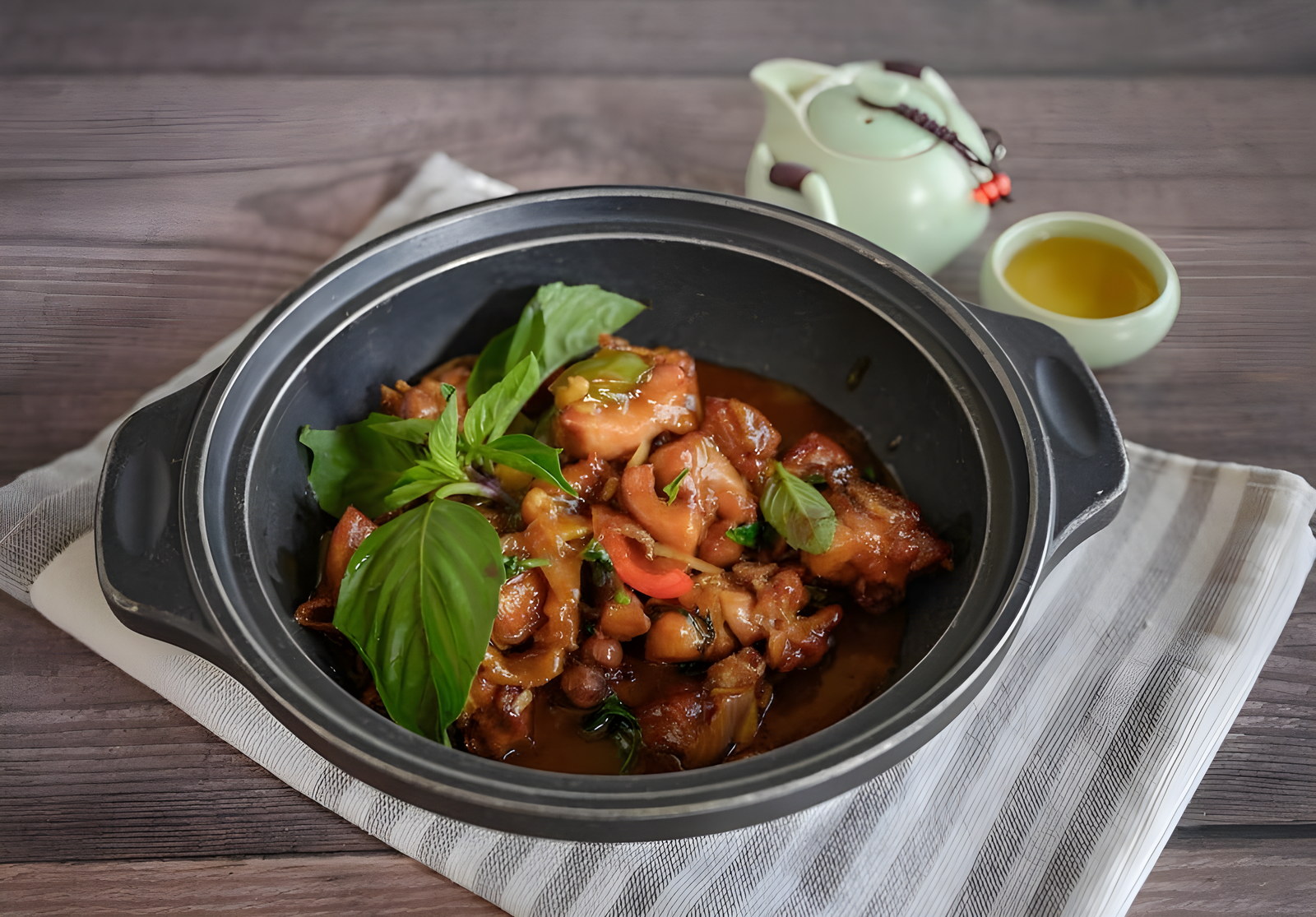 Three-cups chicken in a claypot, set down in the middle of the table